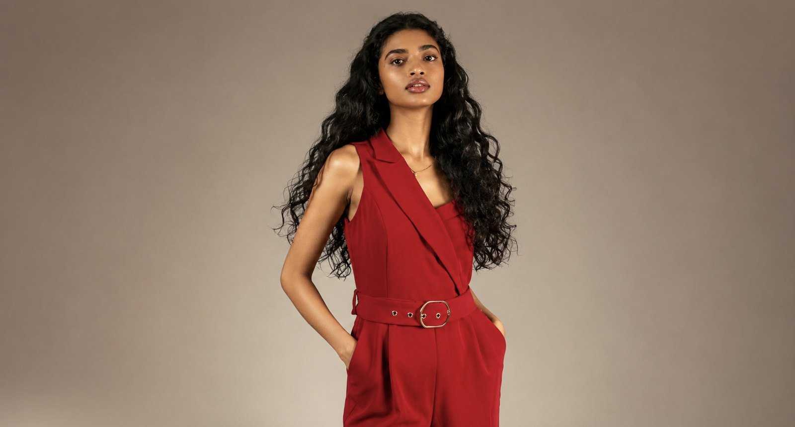 Belted sleeveless red ladies jumpsuit with notch lapel, tailored waist belt and side pockets